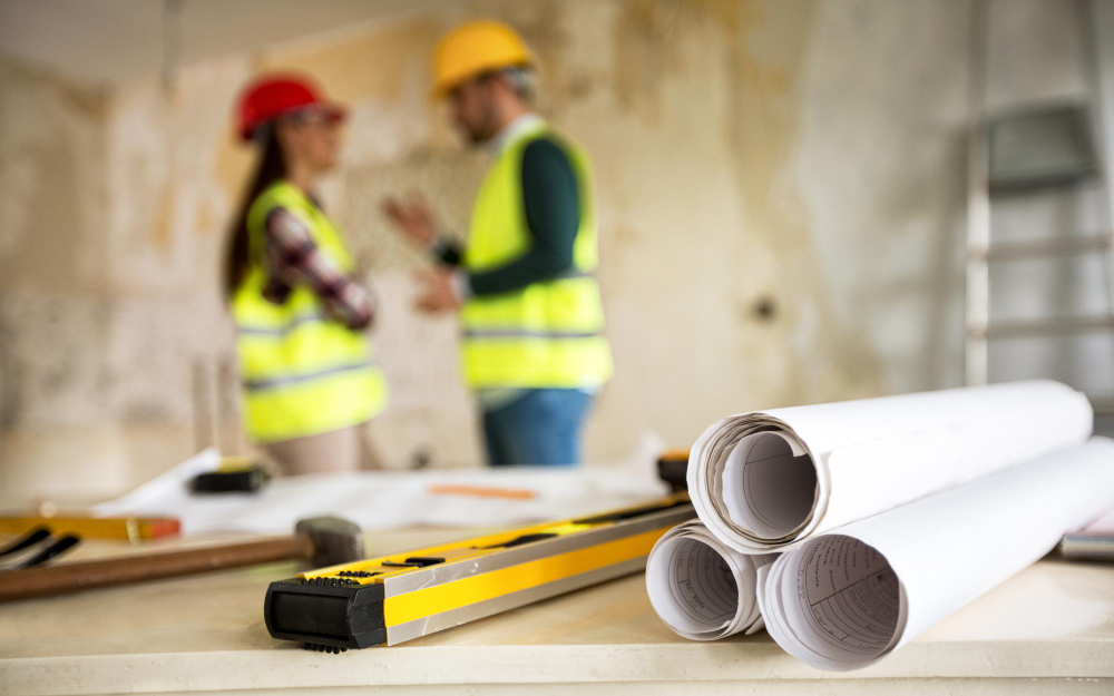 Bouwbedrijf werkers met bouwplannen en bouwgereedschap op locatie