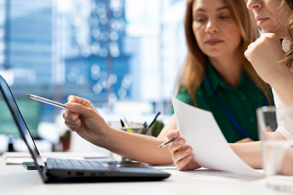 Adviesbureaus bespreken bedrijfsoptimalisatie met laptop en documenten